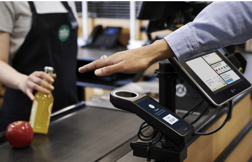 implanted chip in hand waving over scanner at grocery store.